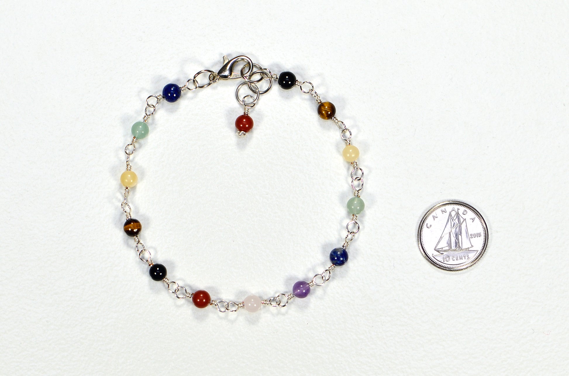 4mm Chakra Gemstone Link Bracelet with Clasp beside a dime.