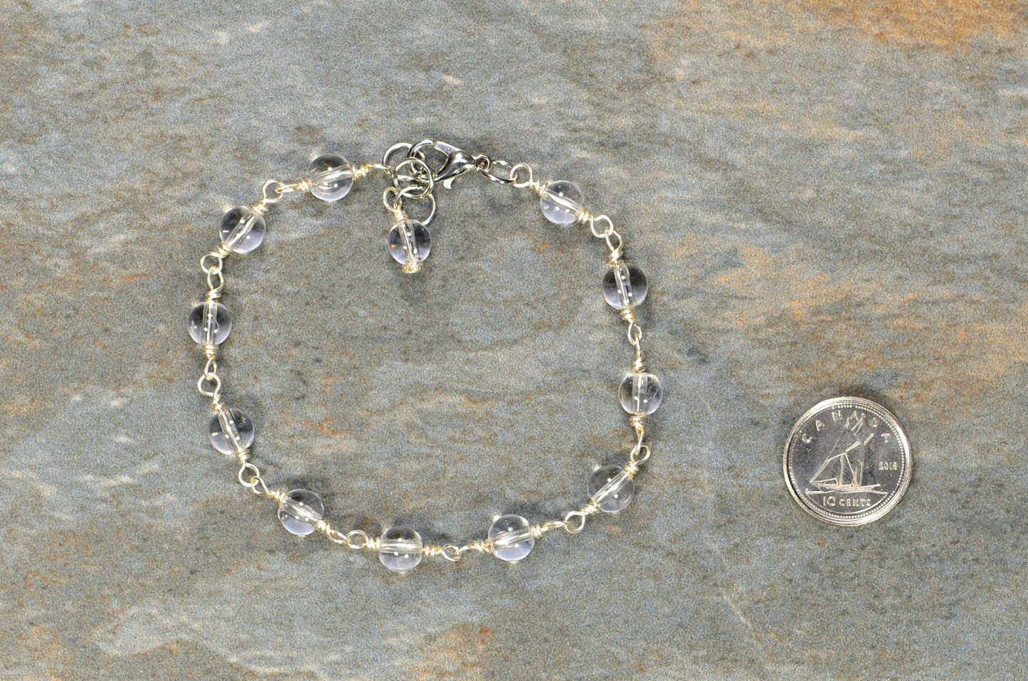  6mm Clear Quartz Link Bracelet beside a dime.