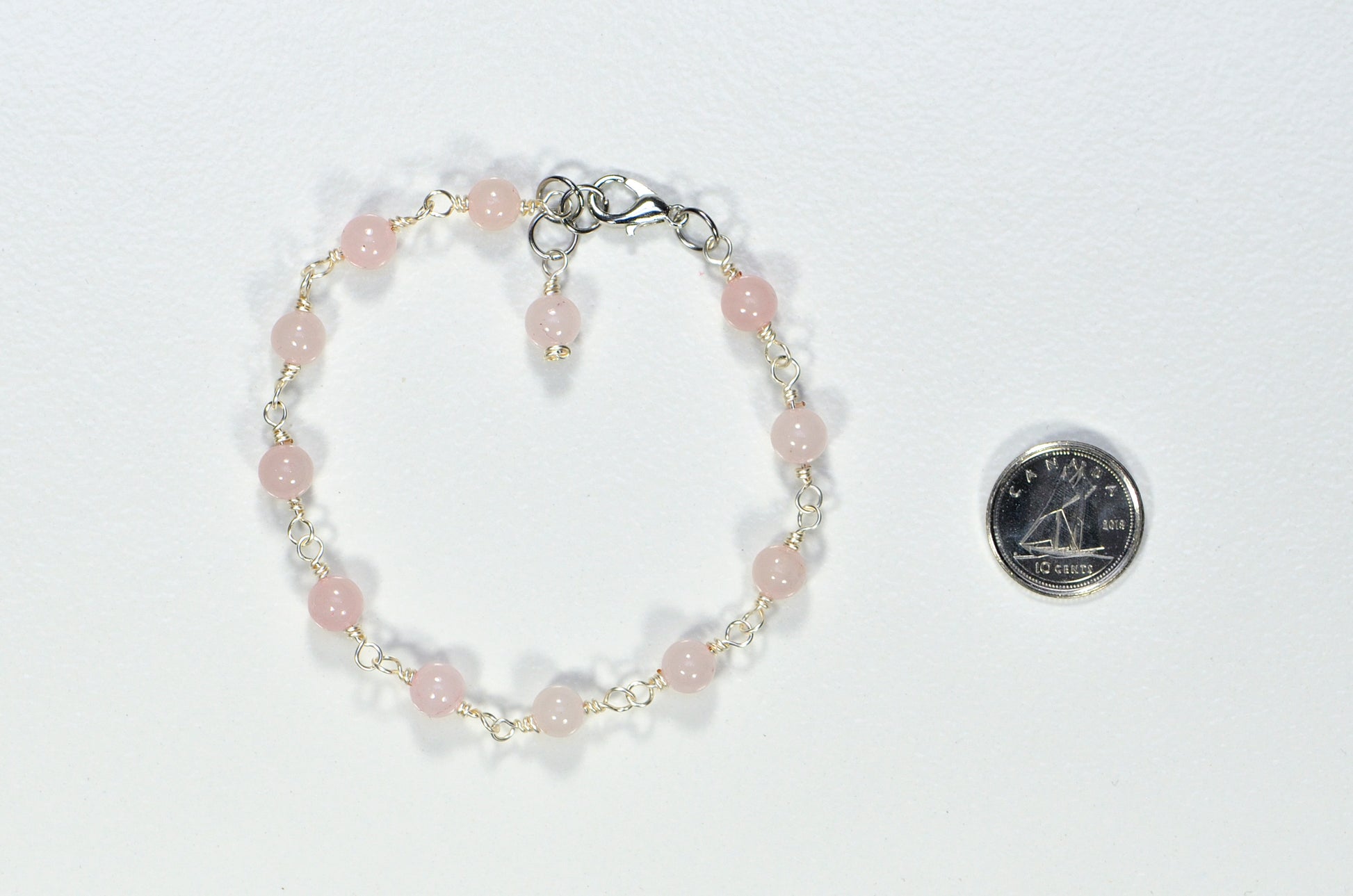 6mm Rose Quartz Link Bracelet beside a dime.