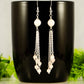 Cascading Rose Quartz Crystal Drop Earrings displayed on a coffee mug.
