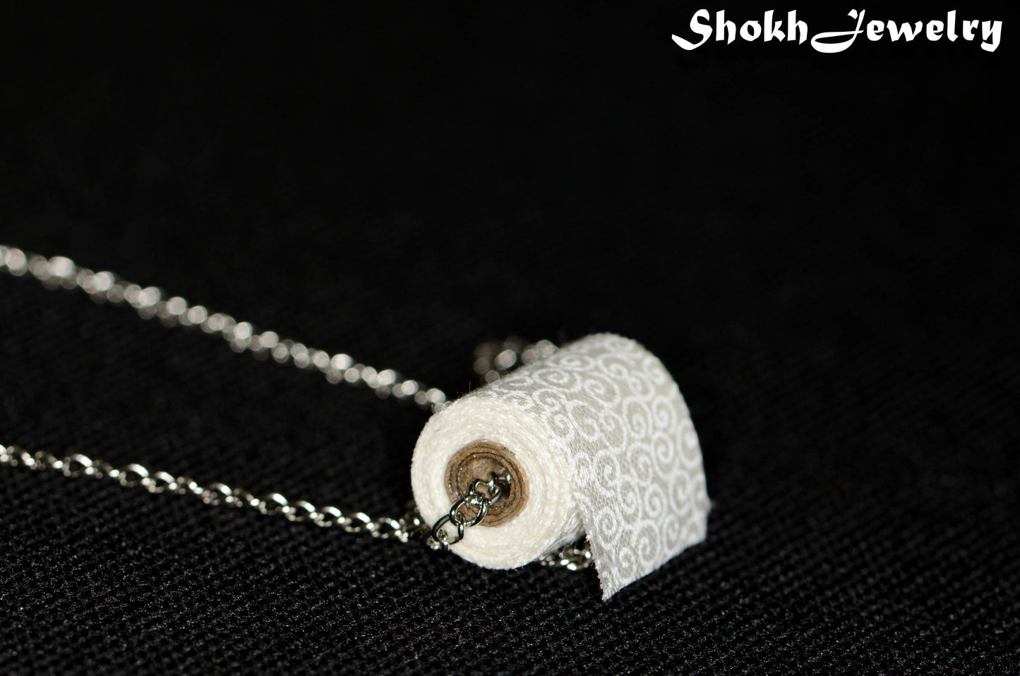 Close up of Miniature Toilet Paper Roll and Dainty Chain Choker Necklace.