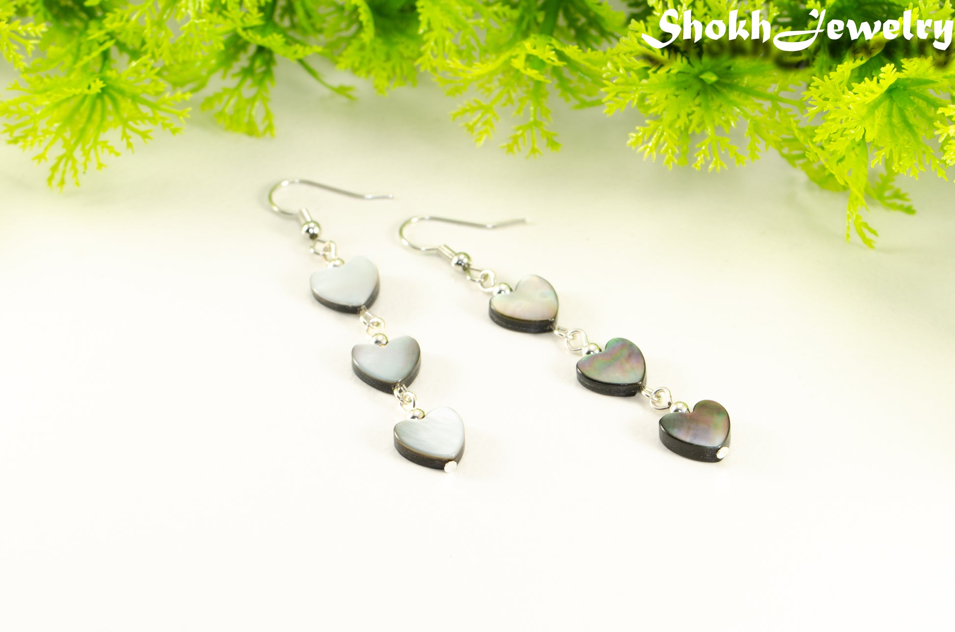 Close up of Long Grey Seashell Hearts Earrings.