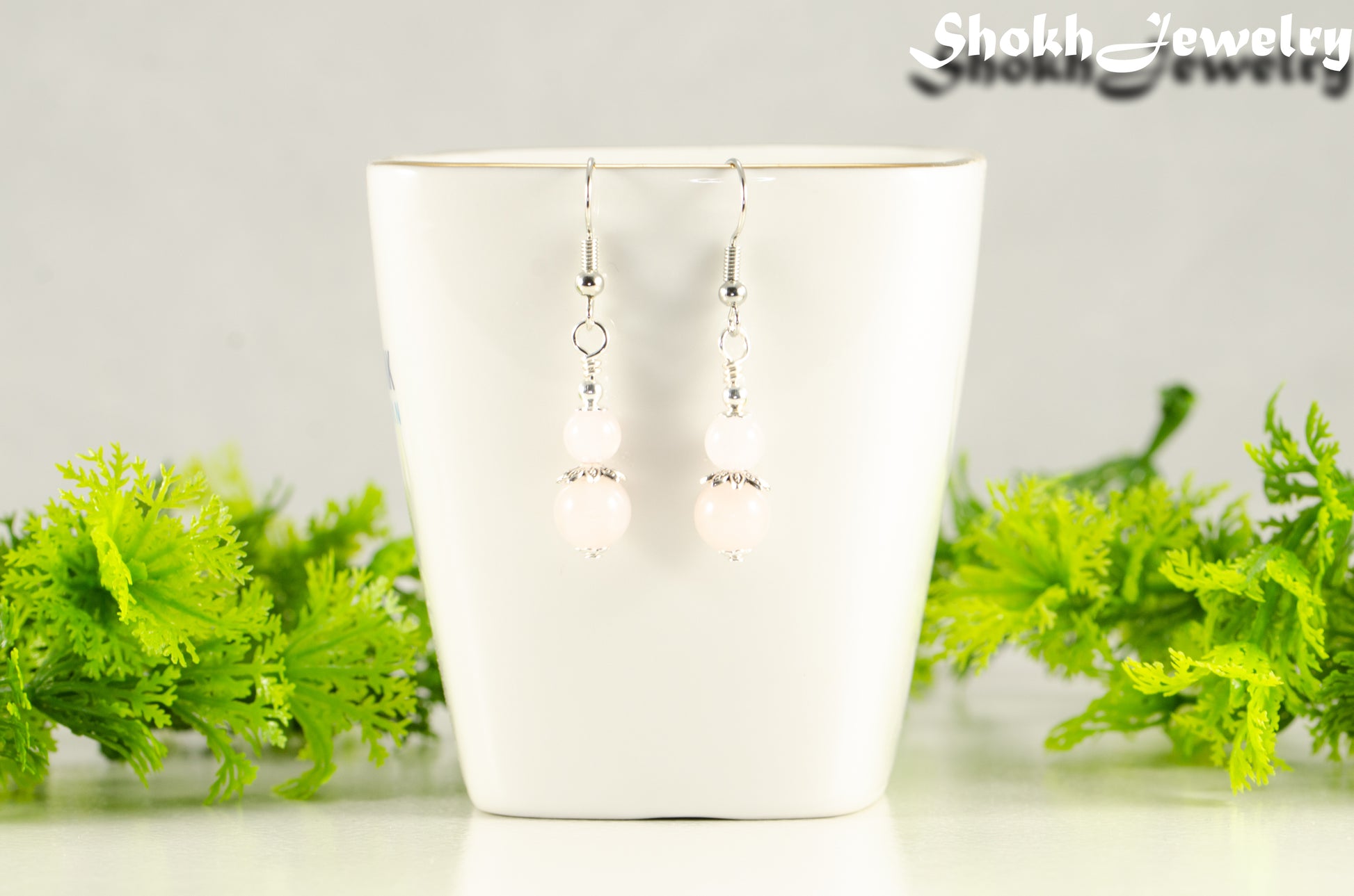 Small Rose Quartz Earrings displayed on a tea cup.