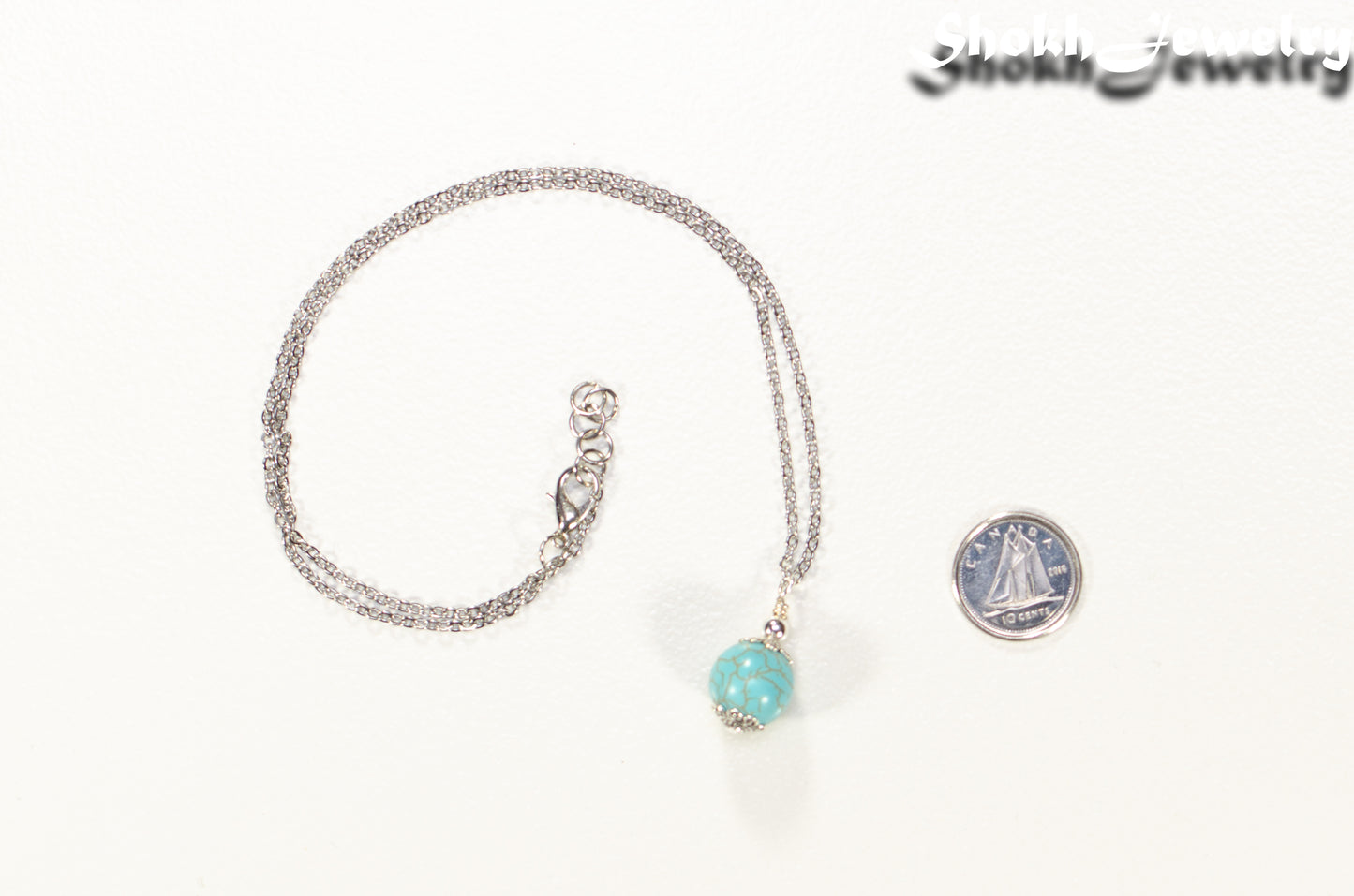 12mm Turquoise Howlite Pendant Necklace beside a dime.