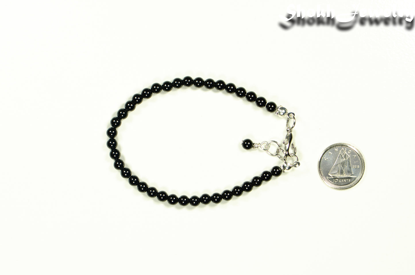 4mm Black Onyx Stone Bracelet with Clasp beside a dime.