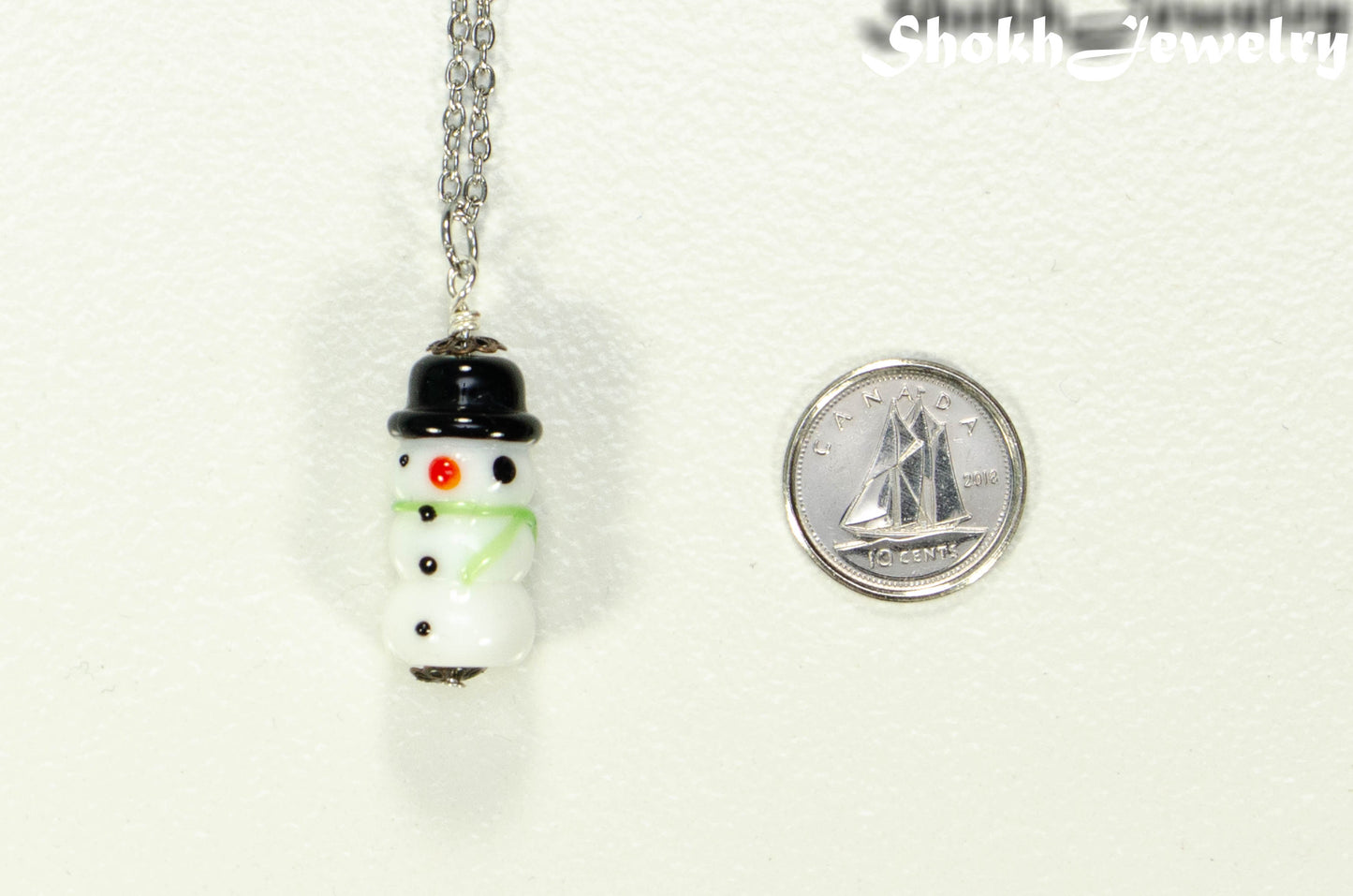 Glass Bead Snowman Pendant beside a dime.