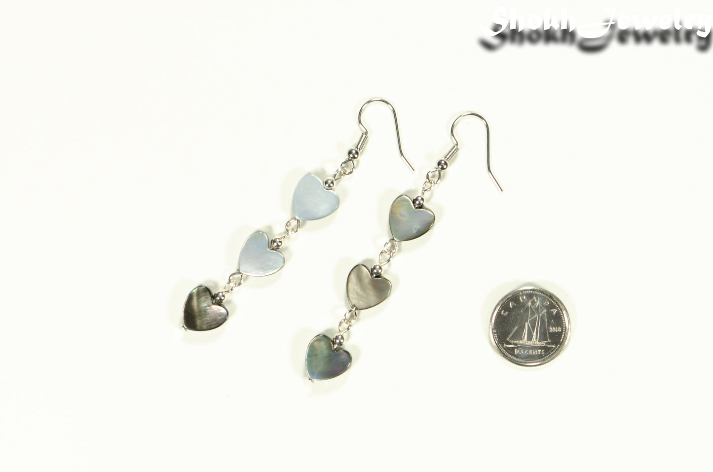 Long Grey Seashell Hearts Earrings beside a dime.