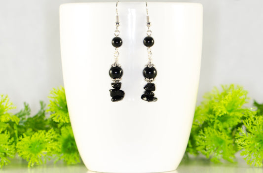 Long Black Obsidian Crystal Chip Earrings displayed on a coffee mug.